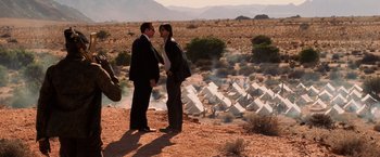 Movie still from “Lord of War” (2005), directed by Andrew Niccol – Two people standing on a hill near a field; Wide shot, Over the shoulder angle