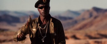 Movie still from “Lord of War” (2005), directed by Andrew Niccol – A man wearing a hat and sunglasses and a military jacket; Close Up shot, Low angle