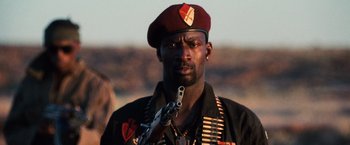 Movie still from “Lord of War” (2005), directed by Andrew Niccol – A man in a red beret holding a rifle; Close Up shot, Low angle