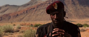 Movie still from “Lord of War” (2005), directed by Andrew Niccol – A man wearing a maroon hat and a black jacket; Close Up shot, Low angle