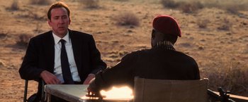 Movie still from “Lord of War” (2005), directed by Andrew Niccol – Two men sitting at a table in the desert; Medium shot, Over the shoulder angle