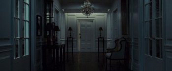 Movie still from “Lord of War” (2005), directed by Andrew Niccol – A dark room with two lamps and a chandelier in it; Wide shot, Low angle