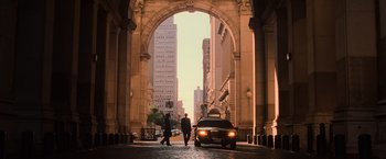 A man walking down a street under an archway