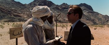 Movie still from “Lord of War” (2005), directed by Andrew Niccol – A man talking to two men in a desert area; Close Up shot, Over the shoulder angle