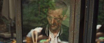 Movie still from “Lost Bullet 2: Back for More” (2022), directed by Guillaume Pierret – A person with blood on his face; Close Up shot, High angle