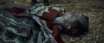 Movie still from “Lost Bullet 2: Back for More” (2022), directed by Guillaume Pierret – A young man is laying on the ground covered with a blanket; Medium shot, High angle
