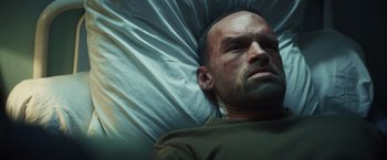 Movie still from “Lost Bullet 2: Back for More” (2022), directed by Guillaume Pierret – A person laying in a bed; Close Up shot, Overhead angle