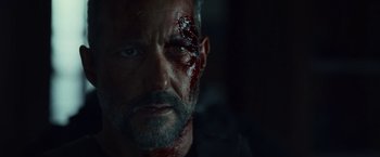 Movie still from “Lost Bullet 2: Back for More” (2022), directed by Guillaume Pierret – A person with blood on his face; Close Up shot, Over the shoulder angle