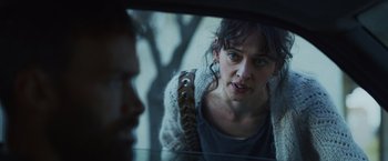 Movie still from “Lost Bullet 2: Back for More” (2022), directed by Guillaume Pierret – A woman looking into a mirror while holding a purse; Close Up shot, Over the shoulder angle