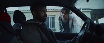 Movie still from “Lost Bullet 2: Back for More” (2022), directed by Guillaume Pierret – A man and a woman in the back seat of a car; Medium shot, Over the shoulder angle