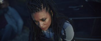 Movie still from “Lost Bullet 2: Back for More” (2022), directed by Guillaume Pierret – A person with dreads looking down; Close Up shot, High angle