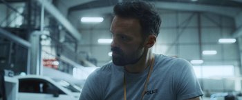 Movie still from “Lost Bullet 2: Back for More” (2022), directed by Guillaume Pierret – A man with a beard is looking to his left; Close Up shot, Over the shoulder angle