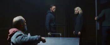 Movie still from “Lost Bullet 2: Back for More” (2022), directed by Guillaume Pierret – A man and a woman standing in front of a table; Medium shot, Over the shoulder angle