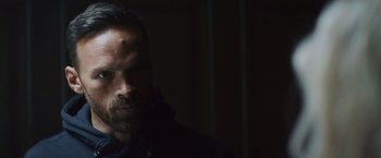 Movie still from “Lost Bullet 2: Back for More” (2022), directed by Guillaume Pierret – A person in a dark room; Close Up shot, Low angle