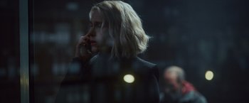 Movie still from “Lost Bullet 2: Back for More” (2022), directed by Guillaume Pierret – A woman talking on a cell phone while standing in front of a window; Close Up shot, Over the shoulder angle