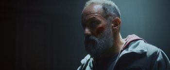Movie still from “Lost Bullet 2: Back for More” (2022), directed by Guillaume Pierret – An old man with a beard and a mustache; Close Up shot, Low angle