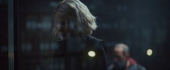 Movie still from “Lost Bullet 2: Back for More” (2022), directed by Guillaume Pierret – A woman with blonde hair standing in front of a window; Close Up shot, Over the shoulder angle