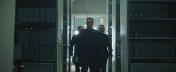 Movie still from “Lost Bullet 2: Back for More” (2022), directed by Guillaume Pierret – A man and two women are standing in a hallway; Medium shot, Low angle