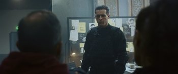 Movie still from “Lost Bullet 2: Back for More” (2022), directed by Guillaume Pierret – A man in a black uniform standing in front of a mirror; Medium shot, Over the shoulder angle