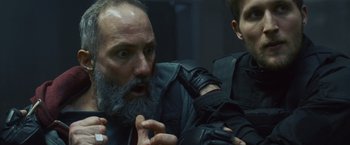 Movie still from “Lost Bullet 2: Back for More” (2022), directed by Guillaume Pierret – A man with a beard and a man with a beard and a jacket; Close Up shot, Over the shoulder angle