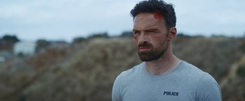 Movie still from “Lost Bullet 2: Back for More” (2022), directed by Guillaume Pierret – A person with a face covered in blood; Close Up shot, Over the shoulder angle