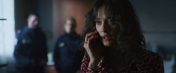 Movie still from “Lost Bullet 2: Back for More” (2022), directed by Guillaume Pierret – A woman talking on a cell phone in front of a man; Close Up shot, Over the shoulder angle