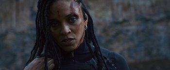 Movie still from “Lost Bullet 2: Back for More” (2022), directed by Guillaume Pierret – A woman with dreadlocks and a black jacket; Close Up shot, Low angle