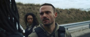 Movie still from “Lost Bullet 2: Back for More” (2022), directed by Guillaume Pierret – A man and a woman are standing next to each other; Close Up shot, Over the shoulder angle