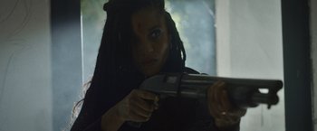 Movie still from “Lost Bullet 2: Back for More” (2022), directed by Guillaume Pierret – A woman with dreadlocks is holding a gun; Close Up shot, Low angle