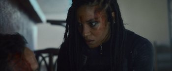 Movie still from “Lost Bullet 2: Back for More” (2022), directed by Guillaume Pierret – A person with dreadlocks; Close Up shot, Over the shoulder angle