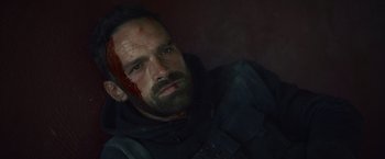Movie still from “Lost Bullet 2: Back for More” (2022), directed by Guillaume Pierret – A person with blood on his face; Close Up shot, Over the shoulder angle
