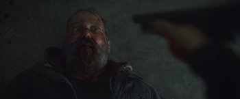 Movie still from “Lost Bullet 2: Back for More” (2022), directed by Guillaume Pierret – A man with a beard is holding a gun in his hand; Close Up shot, Overhead angle
