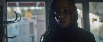 Movie still from “Lost Bullet 2: Back for More” (2022), directed by Guillaume Pierret – A person with dreadlocks looking at the camera; Close Up shot, Low angle