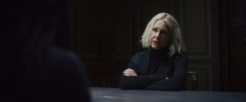 A woman sitting at a table with her arms crossed