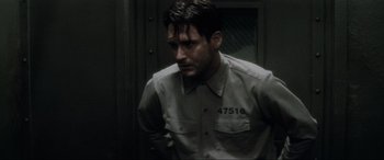 Movie still from “Lost Highway” (1997), directed by David Lynch – A man in a prison uniform standing next to a door; Close Up shot, Over the shoulder angle