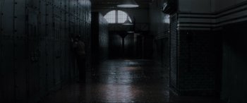 Movie still from “Lost Highway” (1997), directed by David Lynch – A dark hallway with people standing in it; Extreme Wide shot, High angle