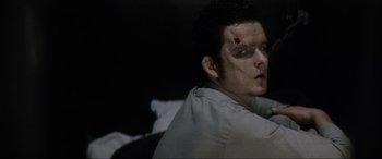 Movie still from “Lost Highway” (1997), directed by David Lynch – A young man with a cut head and a bruise on his face; Close Up shot, Over the shoulder angle