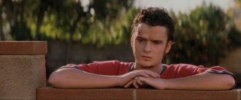 Movie still from “Lost Highway” (1997), directed by David Lynch – A young man leaning on a wall with his arms crossed; Close Up shot, Low angle