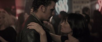 Movie still from “Lost Highway” (1997), directed by David Lynch – A man and a woman embracing each other in front of a neon sign; Close Up shot, Over the shoulder angle