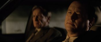 Movie still from “Lost Highway” (1997), directed by David Lynch – Two men in suits and ties sitting in front of each other; Close Up shot, Over the shoulder angle