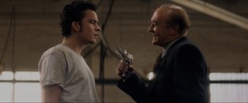 Movie still from “Lost Highway” (1997), directed by David Lynch – A man holding a gun in his hand and another man holding a gun in his other hand; Medium shot, Over the shoulder angle