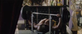 Movie still from “Lost Highway” (1997), directed by David Lynch – A man is lifting a barbell in a bar; Medium shot, Over the shoulder angle