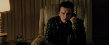 Movie still from “Lost Highway” (1997), directed by David Lynch – A man sitting in a chair talking on a phone; Close Up shot, High angle
