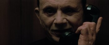 Movie still from “Lost Highway” (1997), directed by David Lynch – An older man is holding a cell phone to his ear; Extreme Close Up shot, Low angle