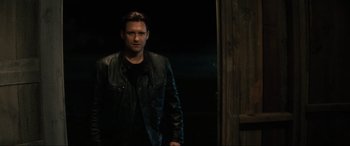Movie still from “Lost Highway” (1997), directed by David Lynch – A man wearing a leather jacket standing next to a wooden wall; Medium shot, Over the shoulder angle