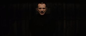 Movie still from “Lost Highway” (1997), directed by David Lynch – A man in a black shirt is in a dark room; Medium shot, Low angle