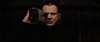 A man holding up a video camera in a dark room