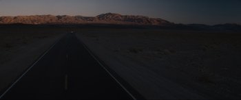 Movie still from “Lost Highway” (1997), directed by David Lynch – A car driving down a road in the middle of the desert; Extreme Wide shot, Low angle