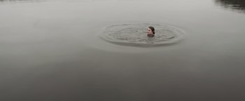 Movie still from “Lotawana” (2022), directed by Trevor Hawkins – A person swimming in a body of water; Extreme Wide shot, High angle