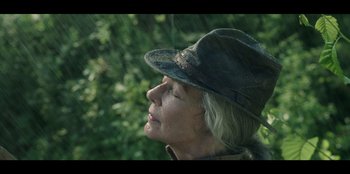 Movie still from “Lou” (2022), directed by Anna Foerster – An older woman wearing a hat looking off into the distance; Close Up shot, Low angle
